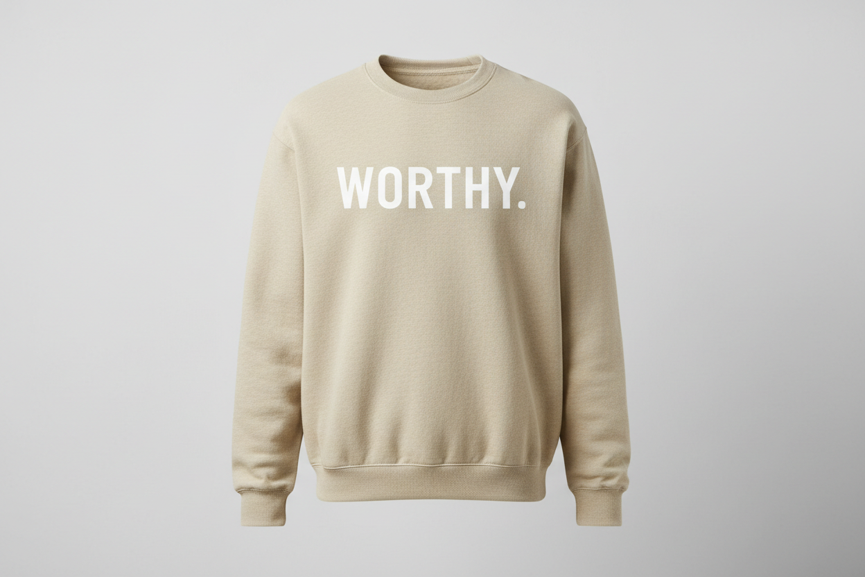 upright image of oatmeal colored crew neck sweatshirt with the word, WORTHY. , going across the front in large white print